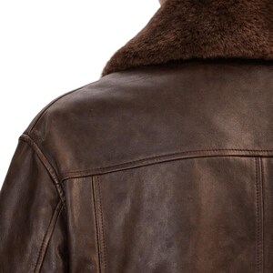 May include: A brown leather jacket with a faux fur collar. The jacket has a classic design with visible stitching details. The image shows the back of the jacket and part of the shoulder.