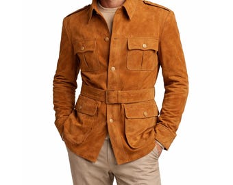 May include: A tan suede jacket with a belted waist and multiple pockets. The jacket has a collared neckline, button closures, and epaulets on the shoulders. The model is wearing a light-colored sweater and khaki pants.