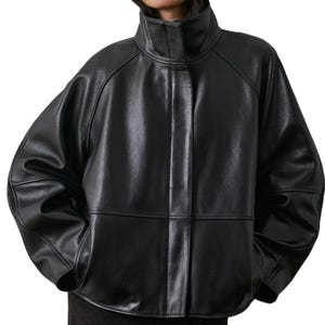 May include: A black leather jacket with a high collar and a loose fit. The jacket has a glossy finish and visible seams. The sleeves are wide, and the overall design is modern and stylish. The jacket is a classic piece of outerwear.