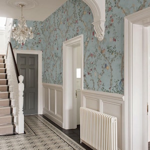 May include: An entryway with light blue floral wallpaper, white wainscoting, and a patterned tile floor. A crystal chandelier hangs from the ceiling. A gray door and staircase are visible.