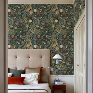 May include: A bedroom featuring a bed with a beige headboard and a patterned wallpaper. The wallpaper has a dark background with colorful birds, lanterns, and floral elements. The bed is made with various pillows in shades of green, orange, and beige.