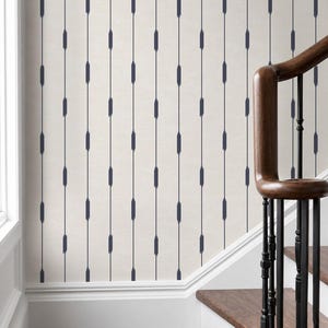 May include: Wallpaper featuring a light cream background with a repeating pattern of vertical dark navy blue lines. Each line is interrupted by small, elongated, brushstroke-style rectangular marks spaced evenly along the length of the stripes.
