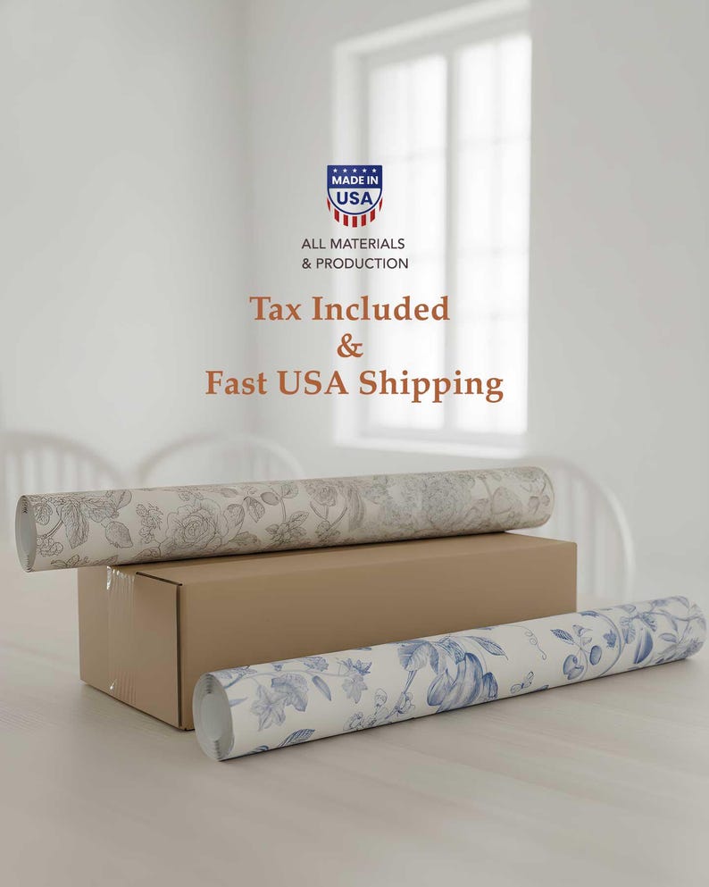 May include: Two rolls of floral wallpaper rest on a cardboard box. One roll features a gray floral pattern, while the other displays a blue floral design. The image also includes text that reads "Made in USA" and "All Materials & Production."