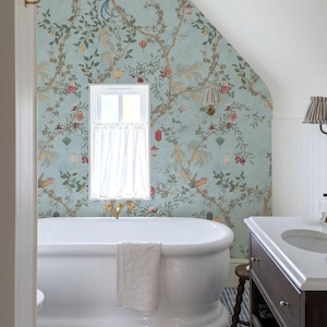 May include: A bathroom with a white clawfoot tub, a dark wood vanity, and a blue and white tiled floor. The walls are adorned with a light blue wallpaper featuring a floral and bird design. A white curtain hangs in the window.