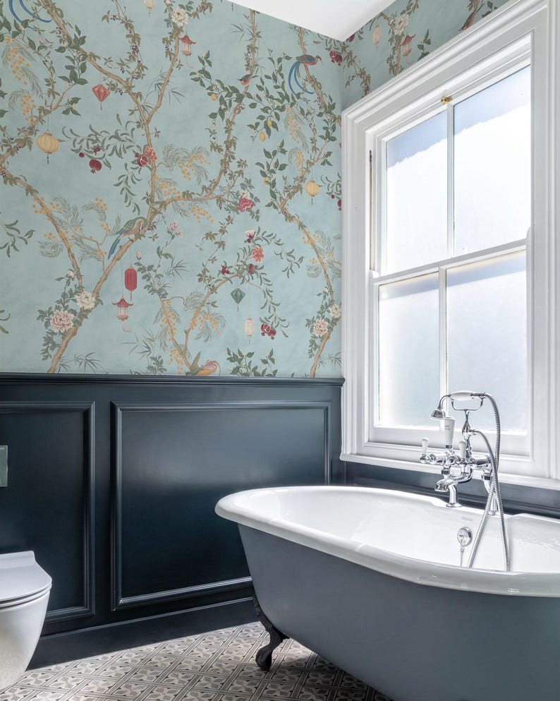 May include: A bathroom with a claw-foot bathtub, a window, and patterned wallpaper. The wallpaper features a light blue background with a floral and bird design. The bathtub is gray with a white interior.