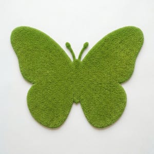 Puede incluir: Una alfombra verde con forma de mariposa con una superficie texturizada y afelpada. La alfombra es de un tono verde vibrante y tiene un dise&ntilde;o sim&eacute;trico. Las alas son grandes y redondeadas, y las antenas son peque&ntilde;as y curvadas. La alfombra est&aacute; dise&ntilde;ada para colocarse en el suelo.