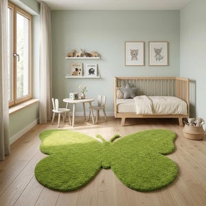 Puede incluir: Una alfombra verde con forma de mariposa domina el dormitorio de un ni&ntilde;o. La habitaci&oacute;n cuenta con una cuna de madera, una peque&ntilde;a mesa y sillas, y arte de animales enmarcados. Las paredes est&aacute;n pintadas de un verde suave y la habitaci&oacute;n est&aacute; llena de luz natural.