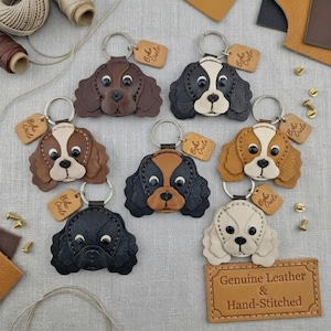 Pode incluir: Seis porta-chaves de couro em forma de cão com argolas de metal e pequenas etiquetas retangulares com a inscrição Boho Circle. Os porta-chaves apresentam várias combinações de cores, incluindo castanho sólido, preto e branco, bege e branco, e preto sólido, todos com detalhes costurados.