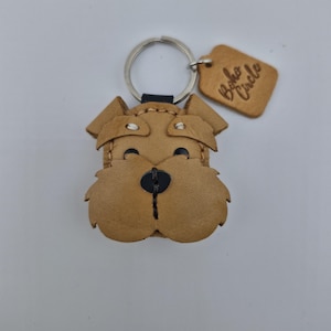 Pu&ograve; includere: Un portachiavi a forma di cane in pelle marrone chiaro, con un portachiavi argentato e un piccolo cartellino. Il viso del cane &egrave; dettagliato con cuciture nere per gli occhi e il naso. Il cartellino recita "Boho Circle".