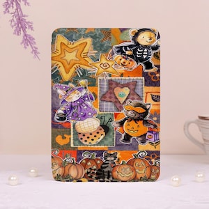 May include: A rectangular decorative plaque featuring a patchwork-style Halloween illustration with a bear in a skeleton costume, a rabbit witch, a cat in a pumpkin mask, stars, pumpkins, and a black cat sitting among orange and green patterns.