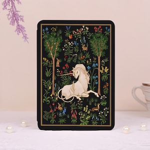 May include: A black rectangular e-reader case featuring a detailed illustration of a white unicorn resting in a lush garden. The scene includes two tall trees, various colorful wildflowers, small rabbits, and a ferret on a dark background.