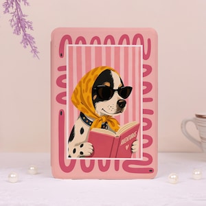 May include: A rectangular pink e-reader case featuring a central illustration of a spotted dog wearing a yellow headscarf and black sunglasses while reading a pink book labeled AVENTURAS. The border has a pink wavy line pattern.