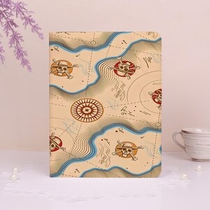 May include: A rectangular tablet case featuring a beige background with a printed map design. The pattern includes blue topographical lines, a brown compass rose, and multiple skull and crossbones icons wearing straw hats in red circles.