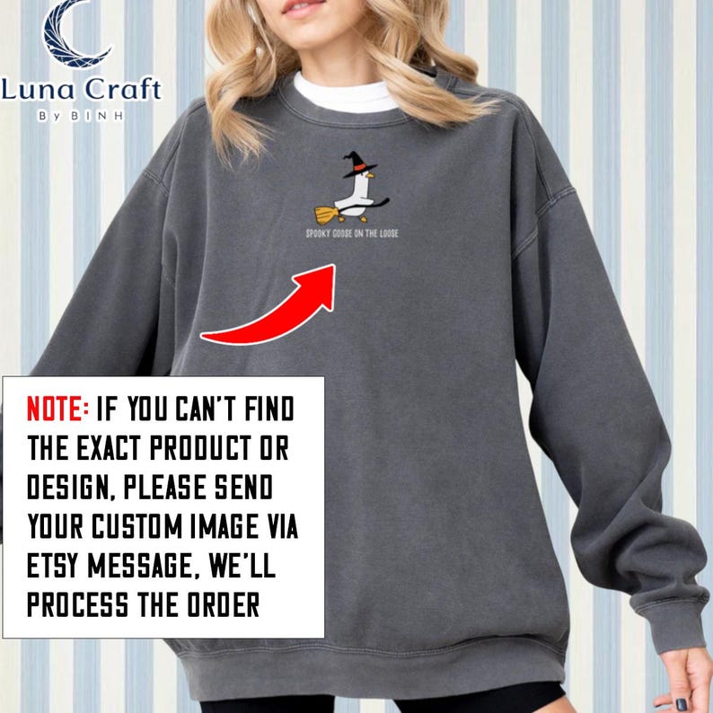 A woman wearing a gray sweatshirt with a graphic of a witch and a bird on it.