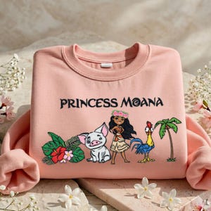 A pink t-shirt with a design featuring characters from the Disney movie " princess Moana" and tropical elements.