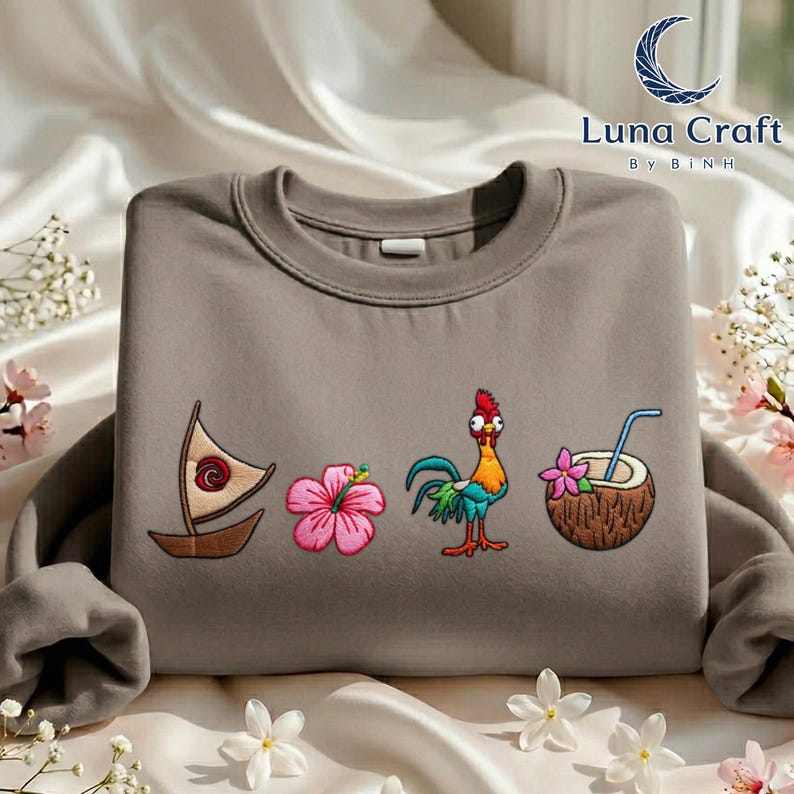 a gray sweatshirt with colorful embroidered designs on it, including a sailboat, a flower, a coconut, and a rooster.