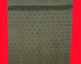 May include: Olive green throw blanket with a textured design. The blanket features rows of small, raised circles and a fringed edge. The top section has horizontal stitched lines. The blanket is made of a soft material.