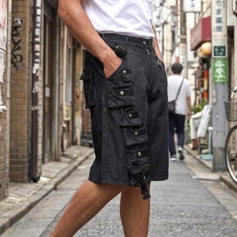 Puede incluir: Pantalones cortos cargo de mezclilla oscura con m&uacute;ltiples bolsillos y detalles de botones plateados. Los pantalones cortos tienen cremallera y trabilla para el cintur&oacute;n. Los pantalones cortos son hasta la rodilla y tienen un estilo casual.