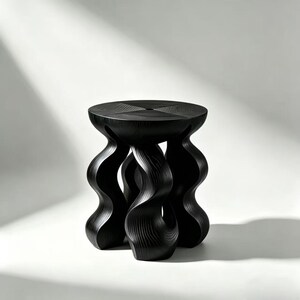 May include: A black wooden stool with a round top and three wavy, sculptural legs. The top has a carved, geometric design. The stool is made of dark wood and stands on a white background.