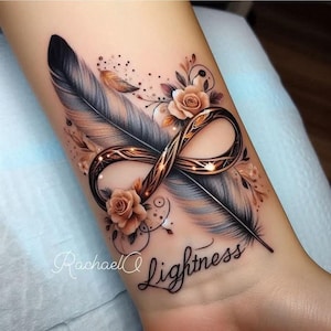 Puede incluir: Un diseño de tatuaje detallado con una pluma, rosas y un símbolo de infinito. El diseño incorpora tonos de gris, marrón y dorado, con la palabra "Lightness" en escritura cursiva. El tatuaje está en la muñeca.