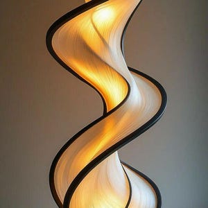 Puede incluir: Una lámpara escultural moderna con un diseño arremolinado en forma de cinta. La lámpara presenta una pantalla clara y texturizada enmarcada por bordes negros, y emite un brillo cálido y acogedor. La base es de color oscuro sólido, proporcionando estabilidad a la pieza artística.