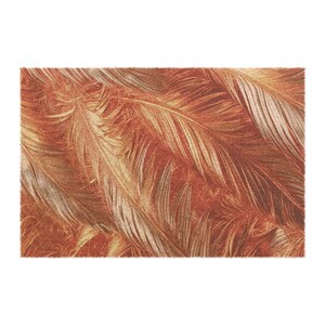 May include: A rectangular rug featuring a repeating pattern of overlapping feathers. The feathers are primarily shades of orange, brown, and cream, creating a warm, textured appearance. The rug's design evokes a natural, organic aesthetic.