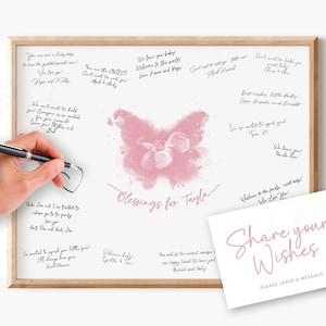 Puede incluir: Un libro de visitas enmarcado para baby shower con un diseño de mariposa rosa y las palabras "Blessings for Tayla". El marco es de madera clara. Una tarjeta con "Share your Wishes" está a la derecha. La imagen está sobre un fondo blanco.