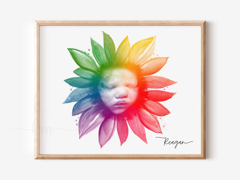 Pu&ograve; includere: Un girasole ad acquerello arcobaleno con il viso di un bambino al centro. Il girasole &egrave; circondato da uno sfondo bianco e il nome "Reagan" &egrave; scritto in corsivo in basso.