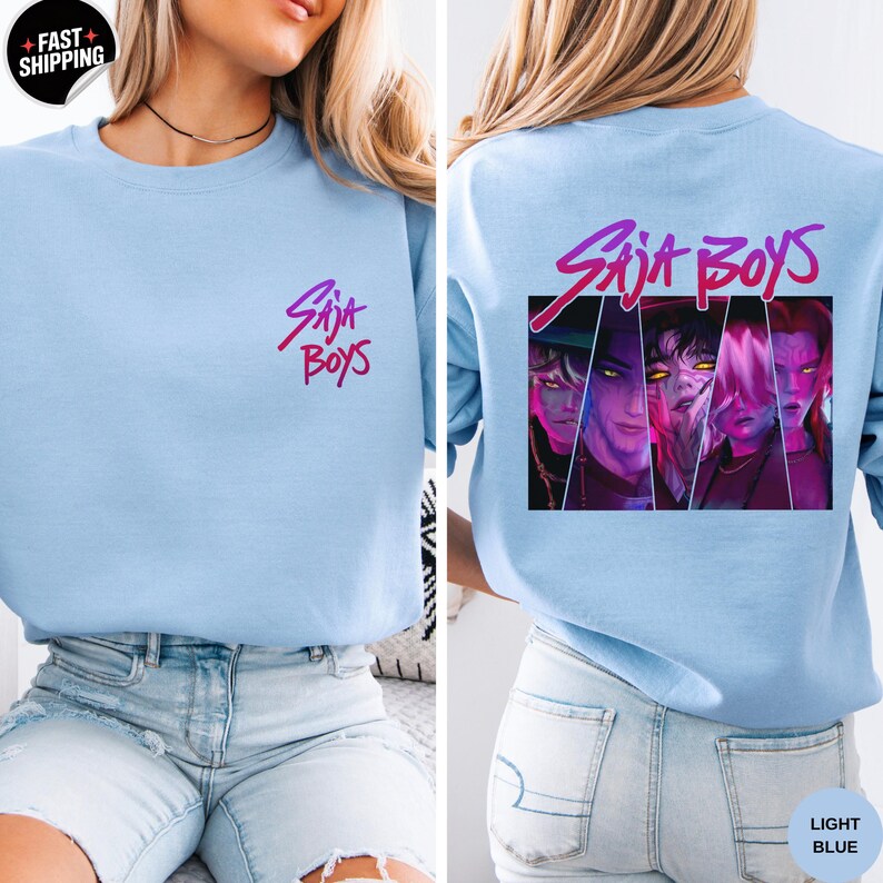 May include: Light blue sweatshirt with the text "Saja Boys" in a gradient pink and purple font on the front and back. The back features a graphic of four stylized faces in a rectangular frame.