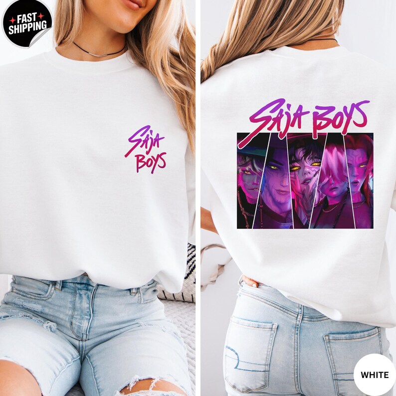 May include: White sweatshirt with the text "Saja Boys" in a gradient purple and pink font on the front and back. The back features a graphic of four stylized faces. The sweatshirt has a crew neck and long sleeves.