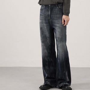 May include: Dark wash denim jeans with a wide leg design. The jeans have a faded effect, transitioning from a lighter shade at the top to a darker shade towards the bottom. The jeans are paired with black shoes.