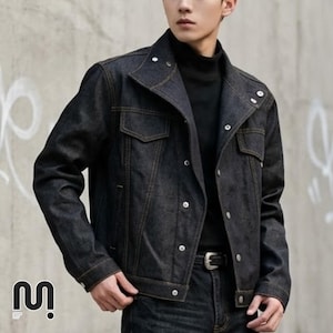 May include: A dark denim jacket with a button-up front, two chest pockets, and a collar. The jacket has a classic design with visible stitching and silver buttons. The model is wearing a black turtleneck underneath. The jacket is a dark wash.