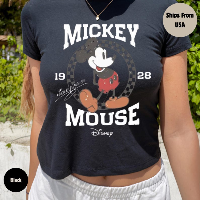 May include: Black crop top featuring a Mickey Mouse graphic. The design includes the word "Mickey" above the character, the year "1928", and the word "Mouse" below. The Disney logo is also visible.