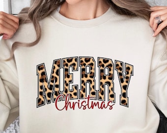 May include: A cream-colored sweatshirt with the words "MERRY" in a bold, leopard print font, and "Christmas" in red script. The sweatshirt is a long-sleeved, crew neck style.