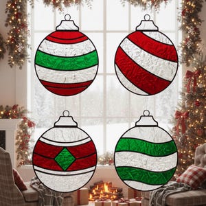May include: Four round Christmas baubles with red, green, and white designs. Each bauble has a silver cap and is hanging in front of a window decorated with Christmas lights and garland. The baubles have different patterns.
