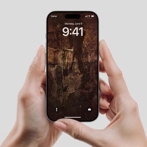 Könnte beinhalten: Ein silbernes Smartphone mit einem braunen und beigefarbenen, strukturierten Hintergrund. Der Bildschirm zeigt die Uhrzeit 9:41 Uhr und das Datum Montag, 6. Juni. Das Telefon wird von zwei Händen vor einem hellgrauen Hintergrund gehalten.