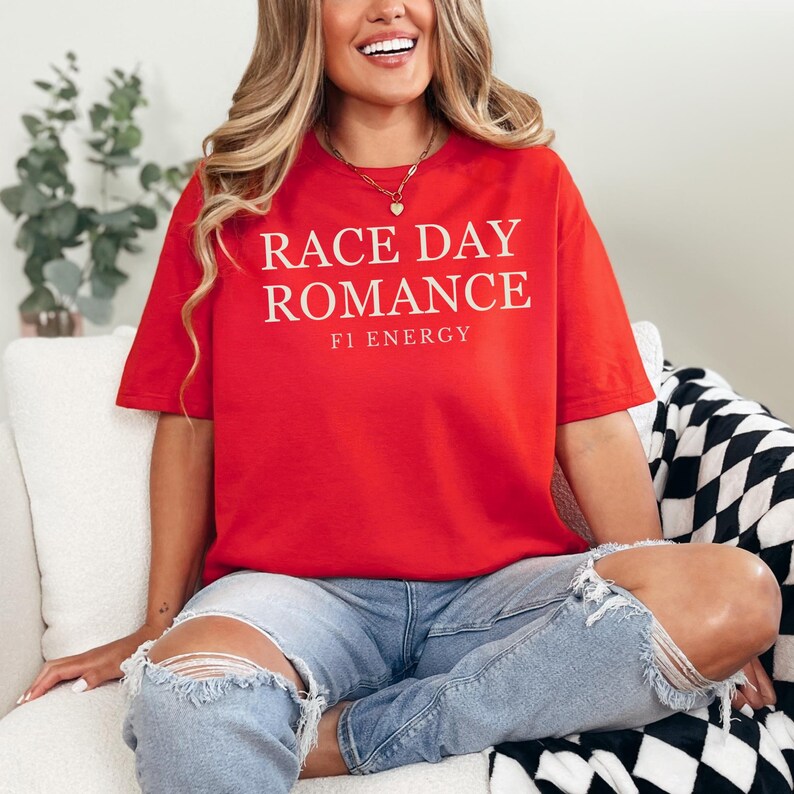 May include: A red t-shirt with the text "RACE DAY ROMANCE" and "F1 ENERGY" in white. The shirt is a short-sleeved, casual style.