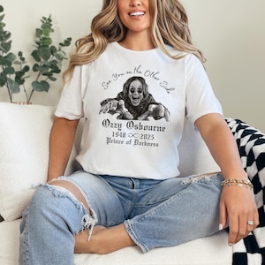 Może przedstawiać: Biała koszulka z czarno-białą grafiką Ozzy'ego Osbourne'a i napisem "See You on the Other Side". Pod grafiką znajduje się napis "Ozzy Osbourne 1948 &infin; 2025 Prince of Darkness."
