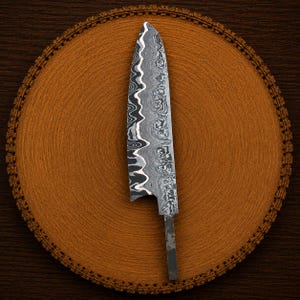 May include: A kitchen knife blade featuring a distinct wavy Damascus steel pattern in shades of silver, gray, and black. The blade has a pointed tip and a curved cutting edge, with a rectangular tang extending from the base for handle attachment.