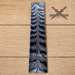 May include: A tall, narrow, rectangular black object featuring a white, intricate, fern-like or tree-branch pattern running vertically through the center. The text "Briastrow Sports" with a crossed-sword logo appears in the upper right corner.