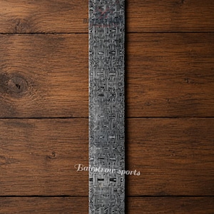 May include: A rectangular metal billet featuring a complex, dark gray and black woven basket-weave pattern across its entire surface. The metal bar displays a high-contrast, layered aesthetic with visible metallic textures and the text Bairstow sports.
