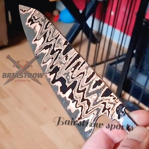 May include: A knife blade featuring a distinct wavy, multi-layered pattern in shades of black, silver, and copper. The blade displays the text Briastrow Sports with a crossed sword logo and the text Bairstrow sports printed on the metal surface.