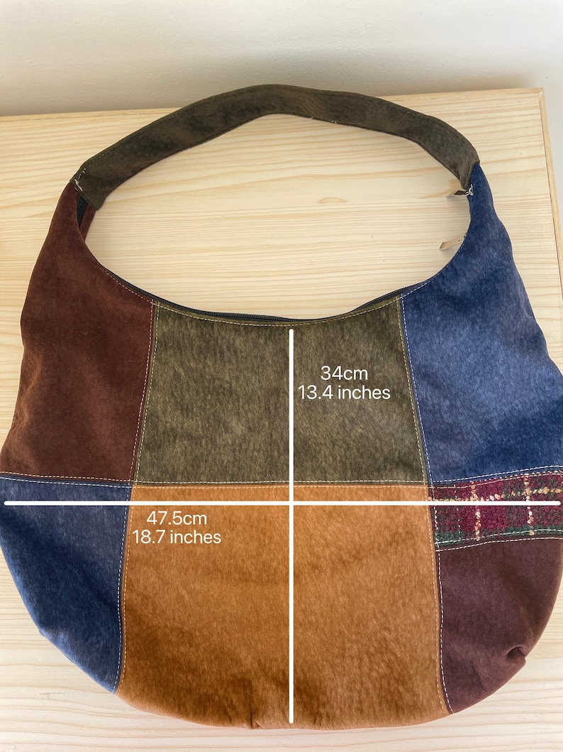 Pu&ograve; includere: Borsa a tracolla patchwork con manico in pelle scamosciata marrone. La borsa &egrave; realizzata con vari tessuti nei toni del marrone, blu e beige. La borsa &egrave; lunga 47,5 cm e larga 34 cm.