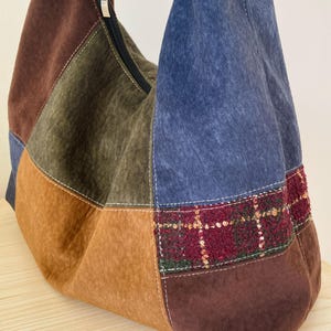 Pu&ograve; includere: Borsa a tracolla patchwork nei toni del marrone, blu e verde oliva. La borsa &egrave; dotata di chiusura con cerniera e di una sezione in tessuto scozzese rosso e verde. La borsa &egrave; realizzata in un materiale morbido simile alla pelle scamosciata.
