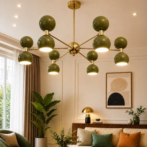 May include: A multi-arm chandelier featuring a central gold-toned metal frame with eight olive green spherical glass shades. Each arm extends from the center, supporting two stacked spheres, with the bottom spheres emitting a warm, bright light.