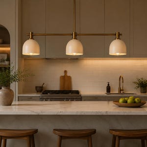 May include: A linear pendant light fitting featuring three matte white dome-shaped shades suspended from a horizontal brass-toned metal bar. The fitting is mounted by a single vertical rod and provides downward illumination from each of the three bulbs.
