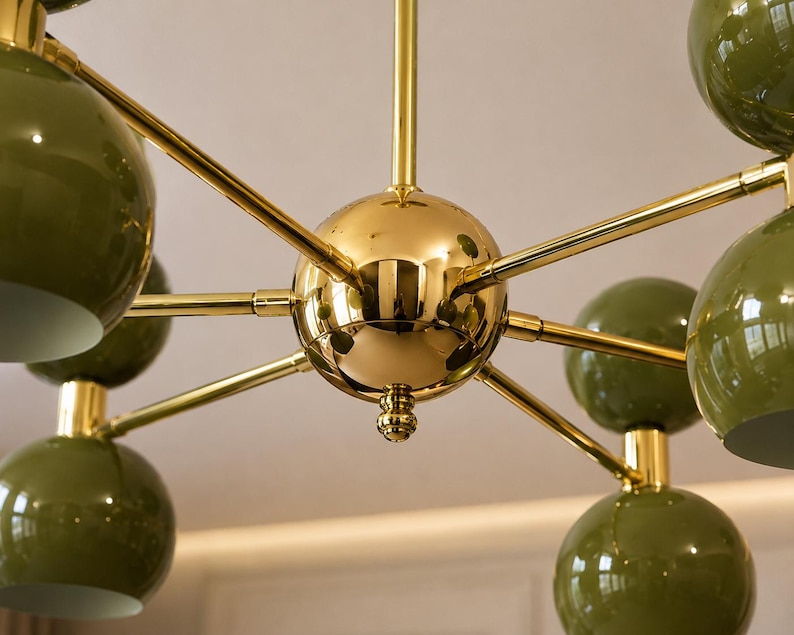 May include: A multi-arm chandelier featuring a central polished gold-tone sphere with radiating arms that extend to support multiple glossy olive green spherical light shades, creating a symmetrical and geometric lighting fixture design.