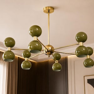 May include: A ceiling chandelier featuring a central gold-toned metal rod and frame with multiple branching arms. Each arm holds two spherical olive green shades, creating a symmetrical arrangement of ten globe-shaped light fixtures in total.