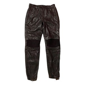 May include: Dark brown leather pants with ribbed knee panels and zippered ankles. The pants have a classic five-pocket design and a zip fly. These pants are a stylish addition to any wardrobe.