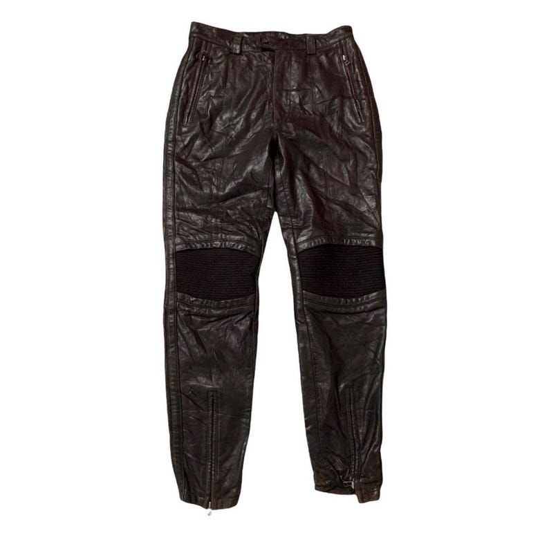 May include: Dark brown leather pants with ribbed knee panels and zippered ankles. The pants have a classic five-pocket design and a zip fly. These pants are a stylish addition to any wardrobe.